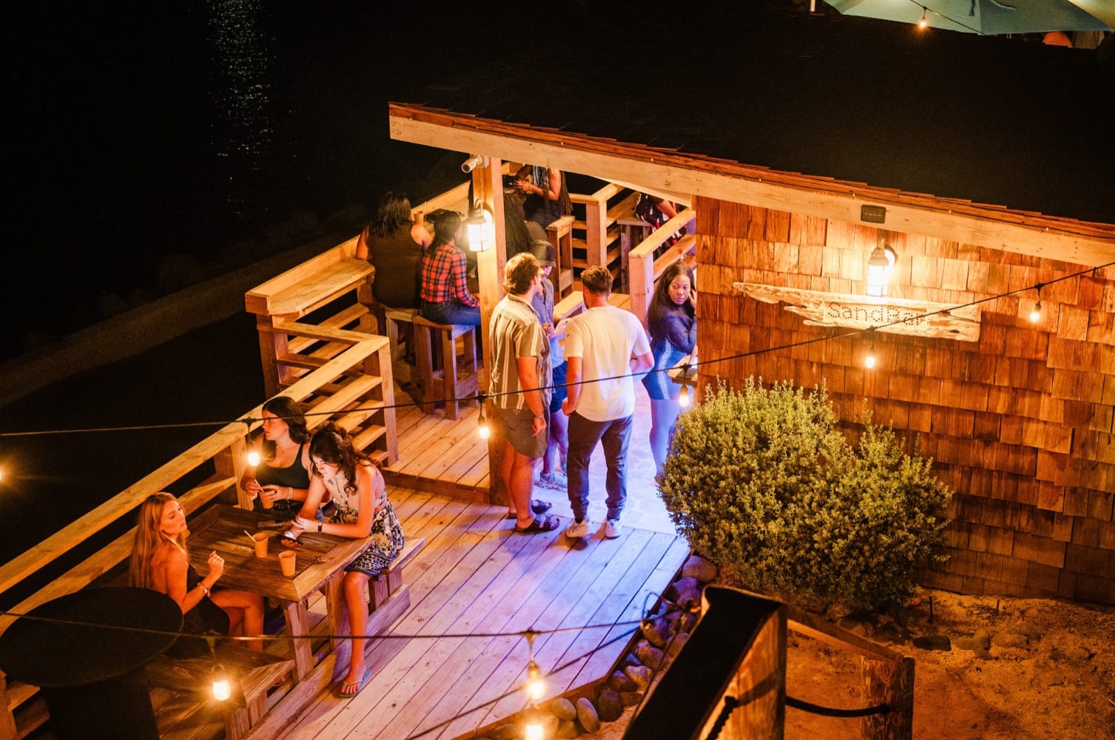 A group gathered on the string-lit deck at night