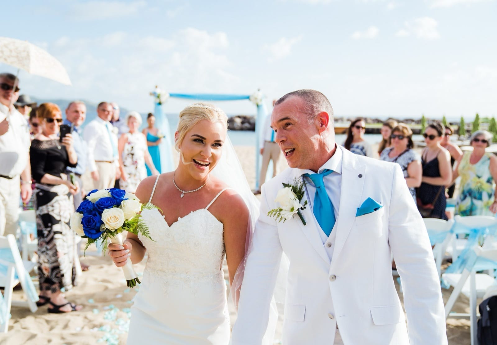 A newlywed couple walking up the aisle at a beach ceremony