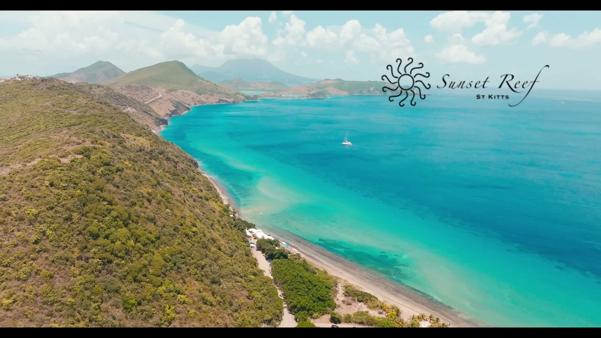 Aerial view of the Sunset Reef coastline, the turquoise Caribbean Sea beside the green hills of St. Kitts